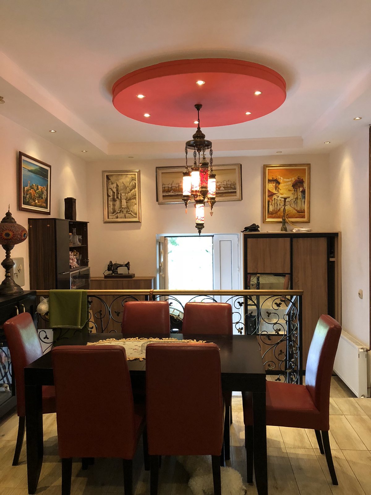Living room with dining area in a mini-hotel, Herceg Novi, Montenegro: red ceiling, vintage chandelier, and furniture.