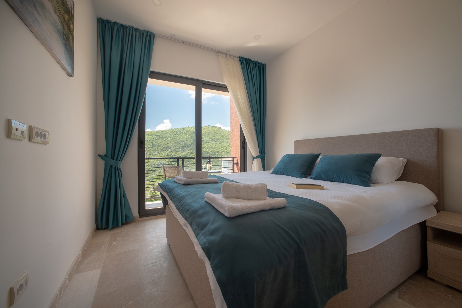 Bedroom with a double bed and mountain view in a villa in Becici, Montenegro: modern interior, panoramic window.