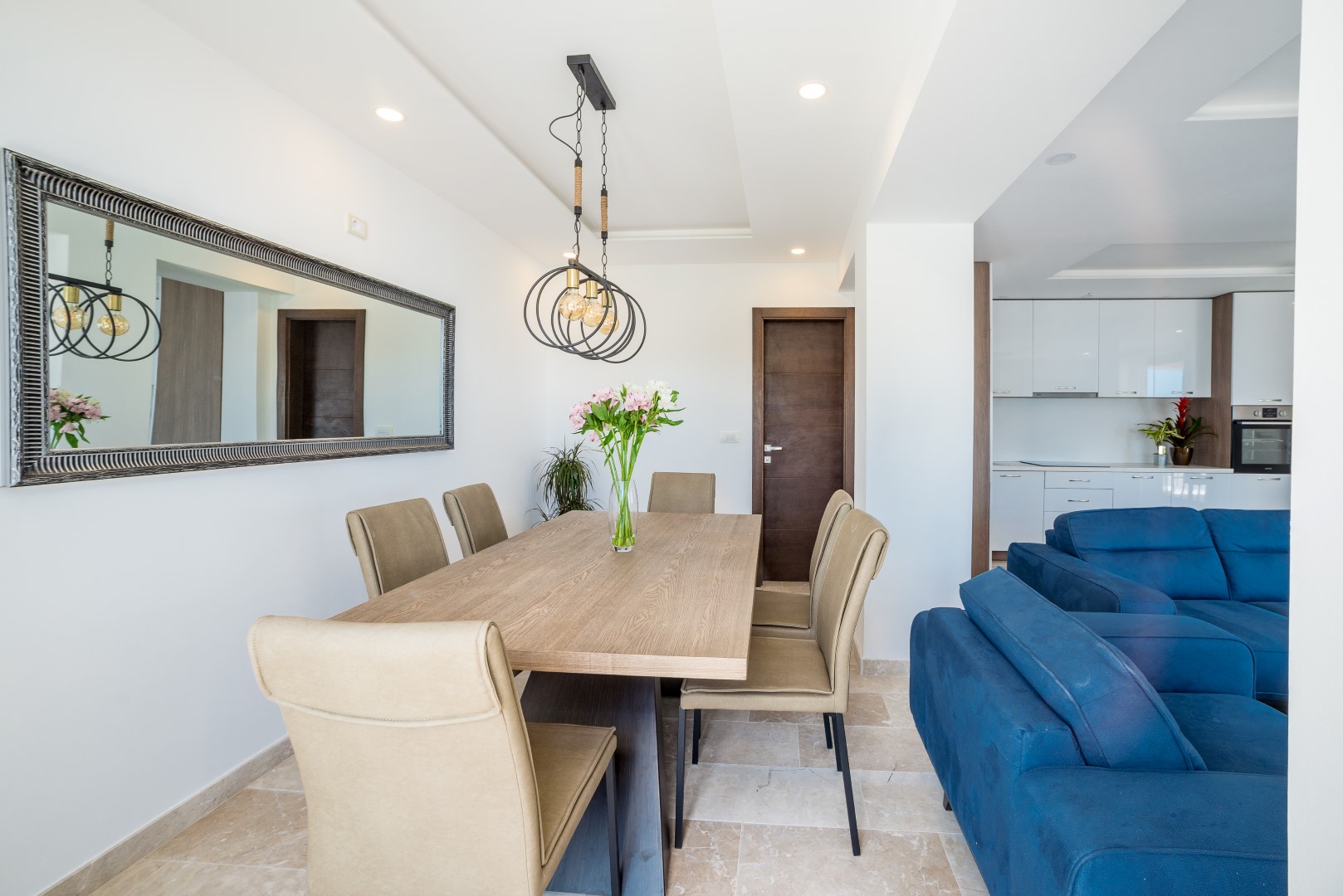 Modern living room with dining area and blue sofa in a villa in Bečići, Montenegro. Bright interior with a mirror.
