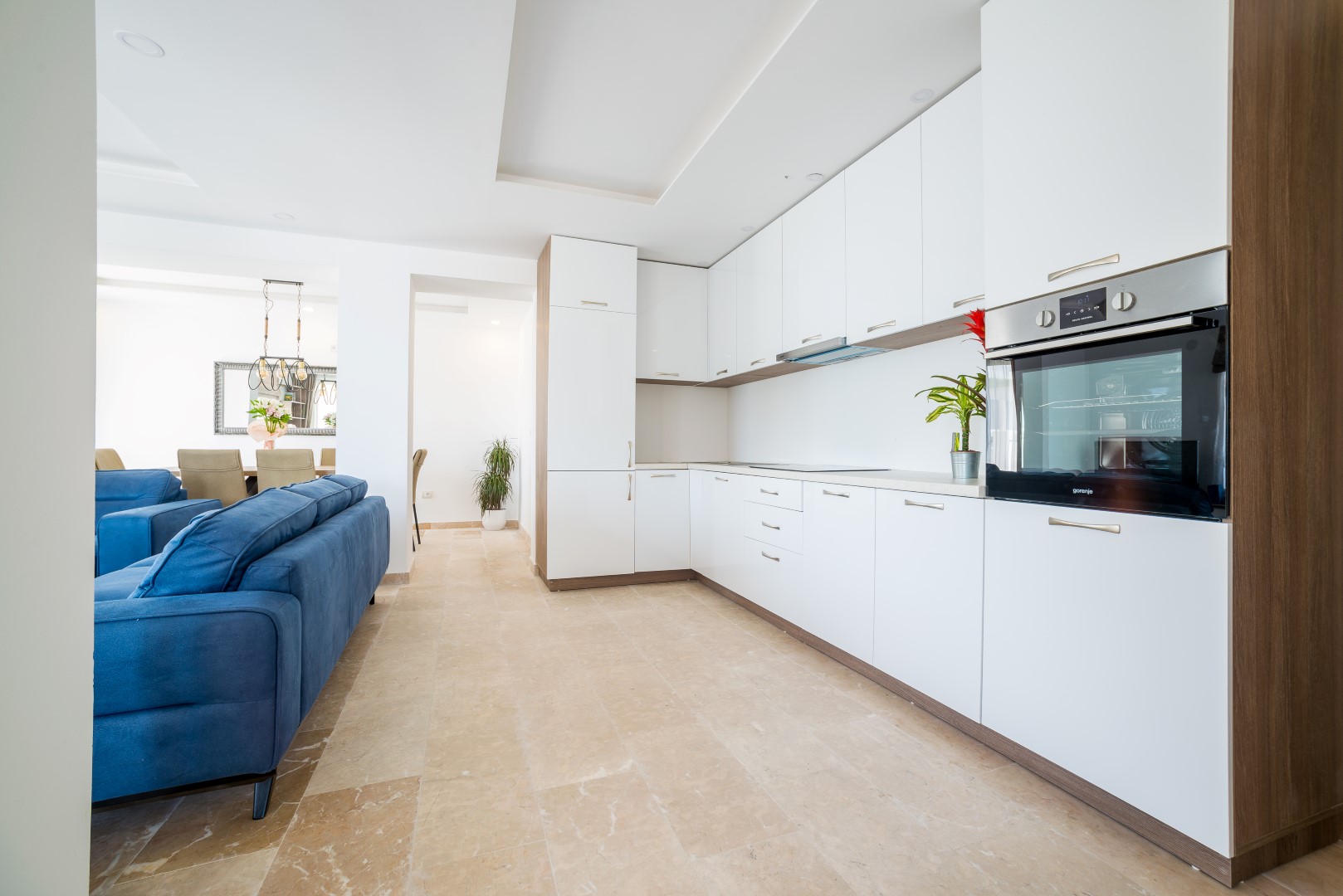 Modern kitchen with white fronts and a blue sofa in the interior of a villa in Bečići, Montenegro.