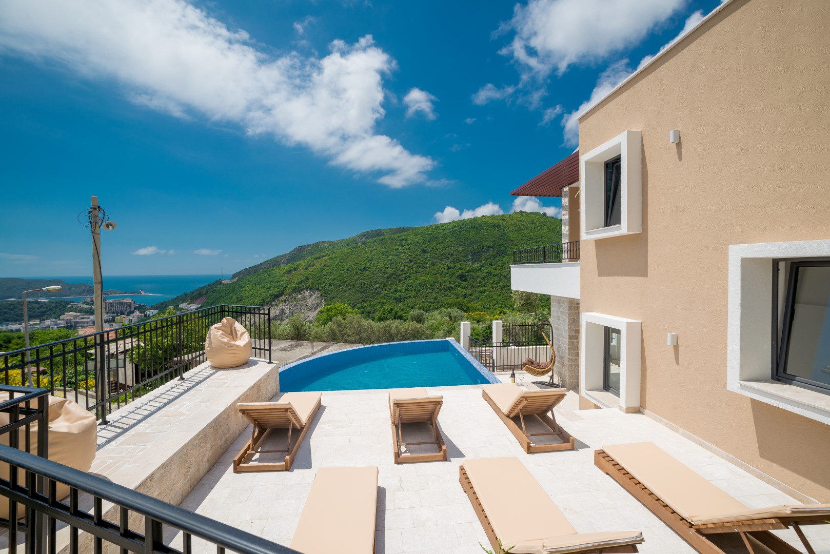 Villa in Bečići, Montenegro: terrace with a pool, sun loungers, and panoramic views of the mountains and the Adriatic Sea.