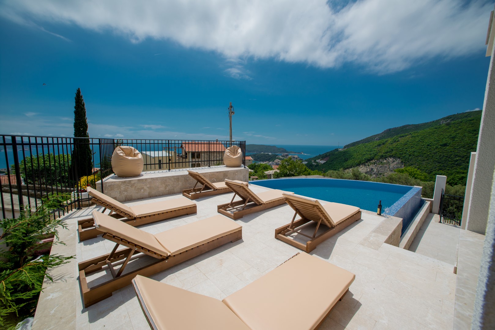 Terrace with a pool and sun loungers at a villa in Bečići, Montenegro, with panoramic sea and mountain views.