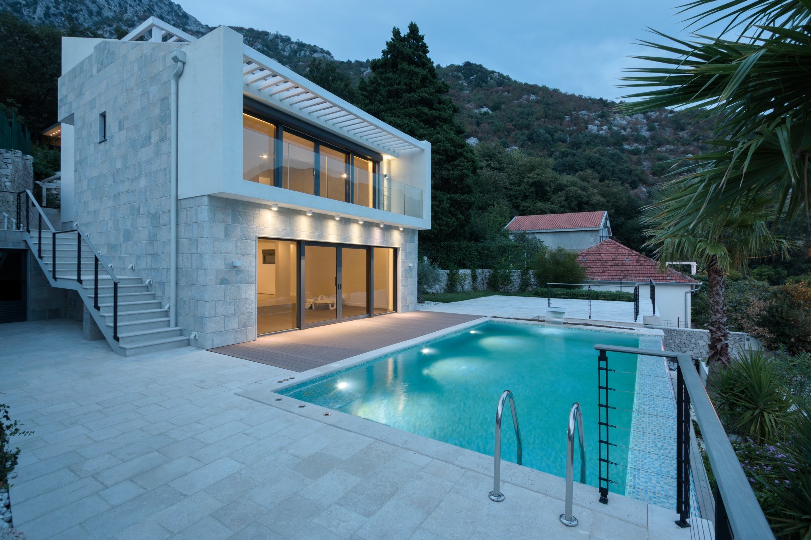 Modern villa with a pool and stone facade in the village of Strp, Montenegro, exterior view in the evening.
