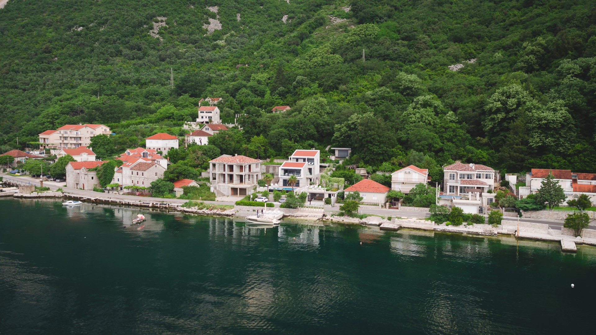 Aerial view of villas and houses by the sea in the village of Strp, Montenegro: coastal property with a private pier.