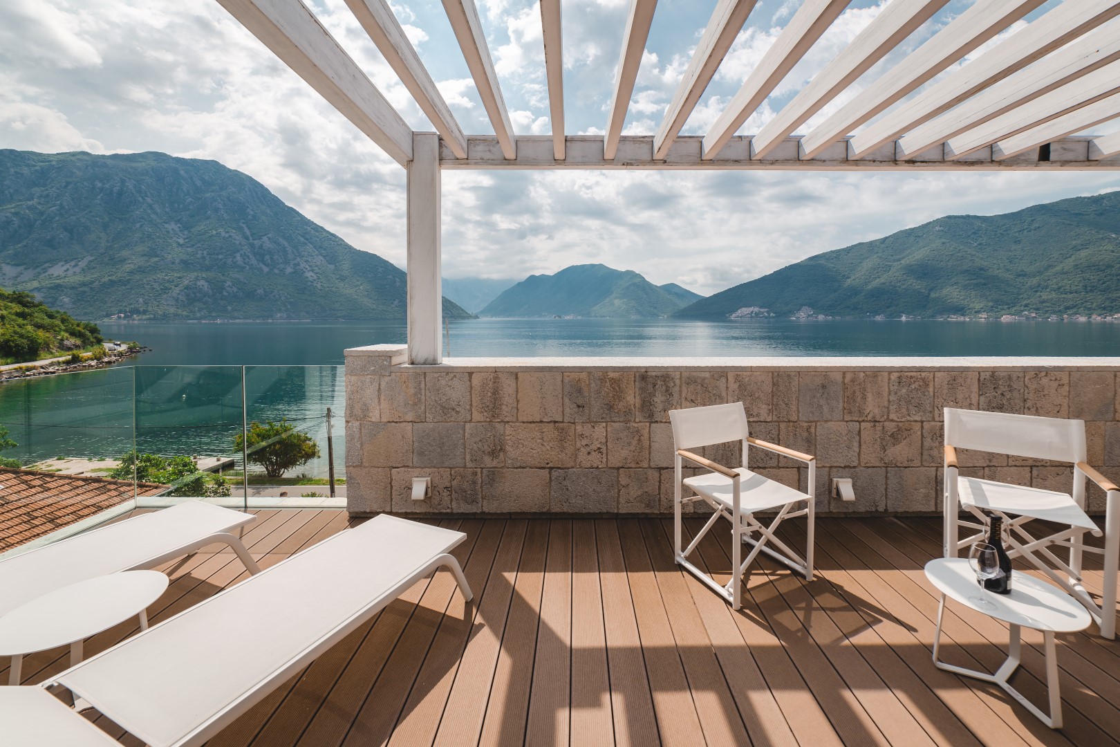 Villa terrace in Strp, Montenegro: wooden decking, white furniture, and panoramic views of Kotor Bay and the mountains.