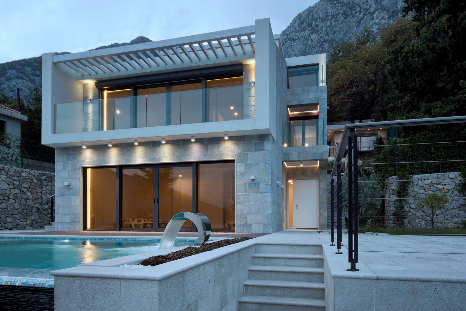 Modern villa with a pool and stone facade in the village of Strp, Montenegro, exterior view in the evening.