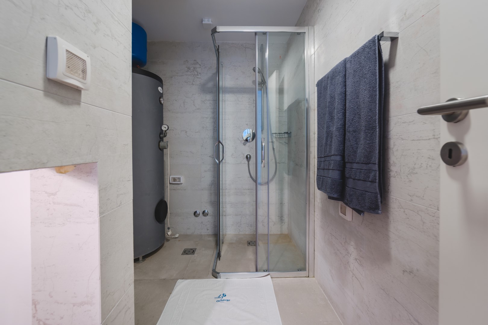 Modern bathroom with a shower cabin and boiler in a villa in Strp, Montenegro. Light tile finish.