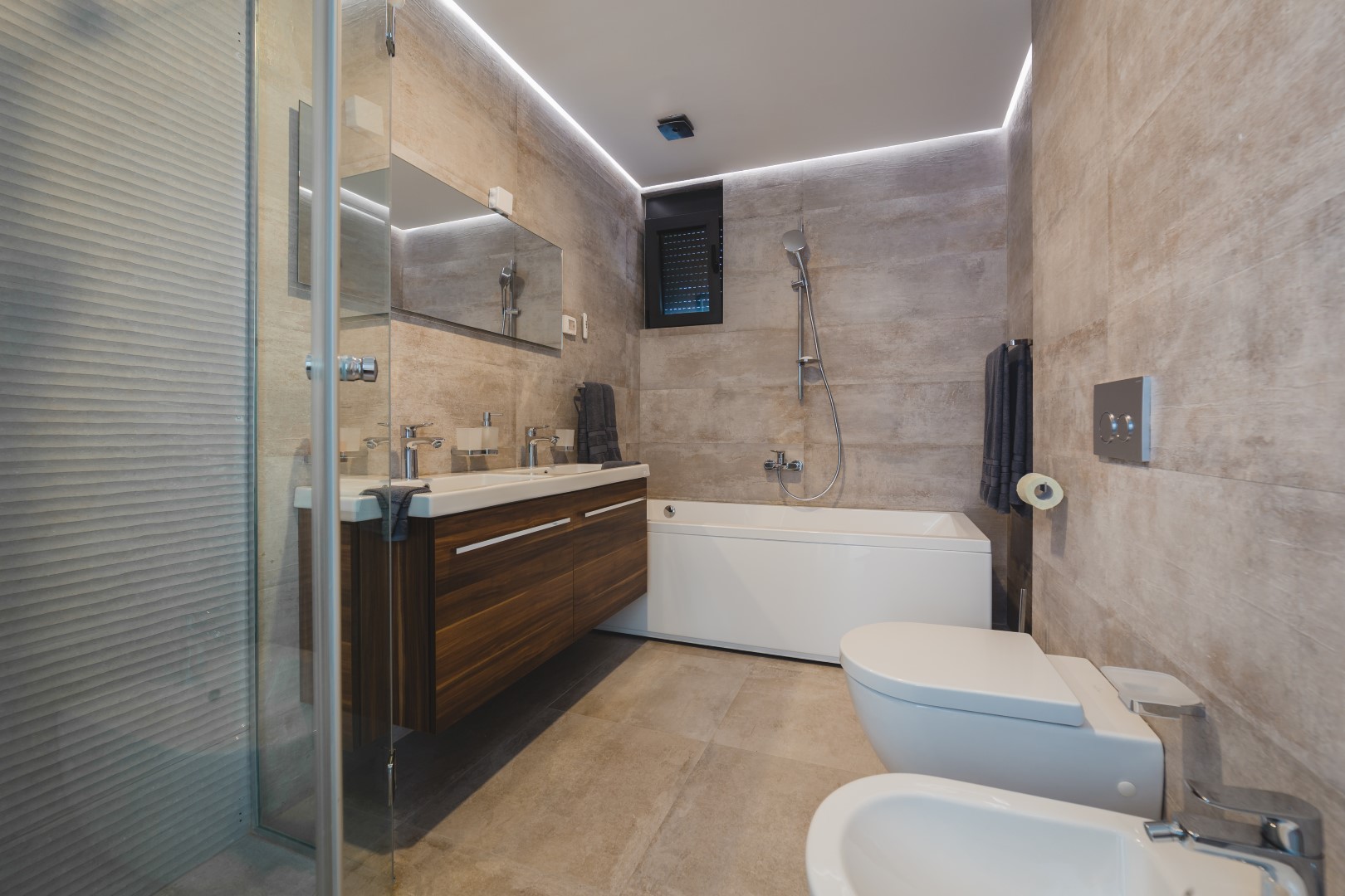 Modern bathroom with a bathtub and shower in a villa, Strp, Montenegro: stylish stone-look finishes and wooden furniture.