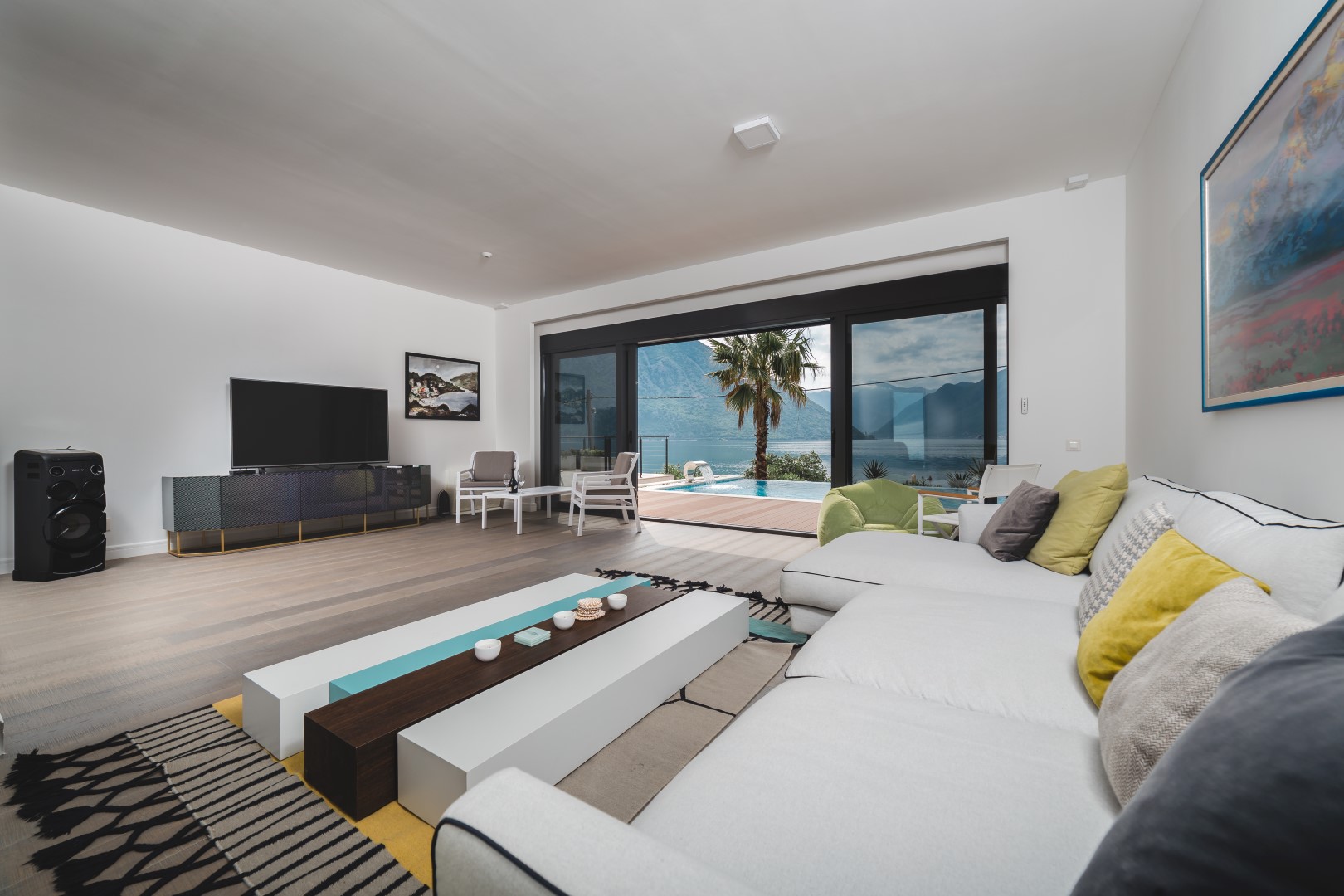 Villa living room in Strp, Montenegro: modern interior, panoramic windows, sea view, pool, and mountains.