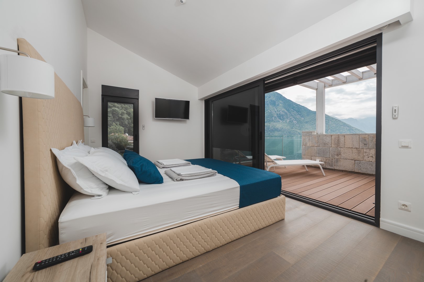 Bedroom in a villa in Strp, Montenegro: double bed, panoramic windows, and a terrace with mountain and sea views.