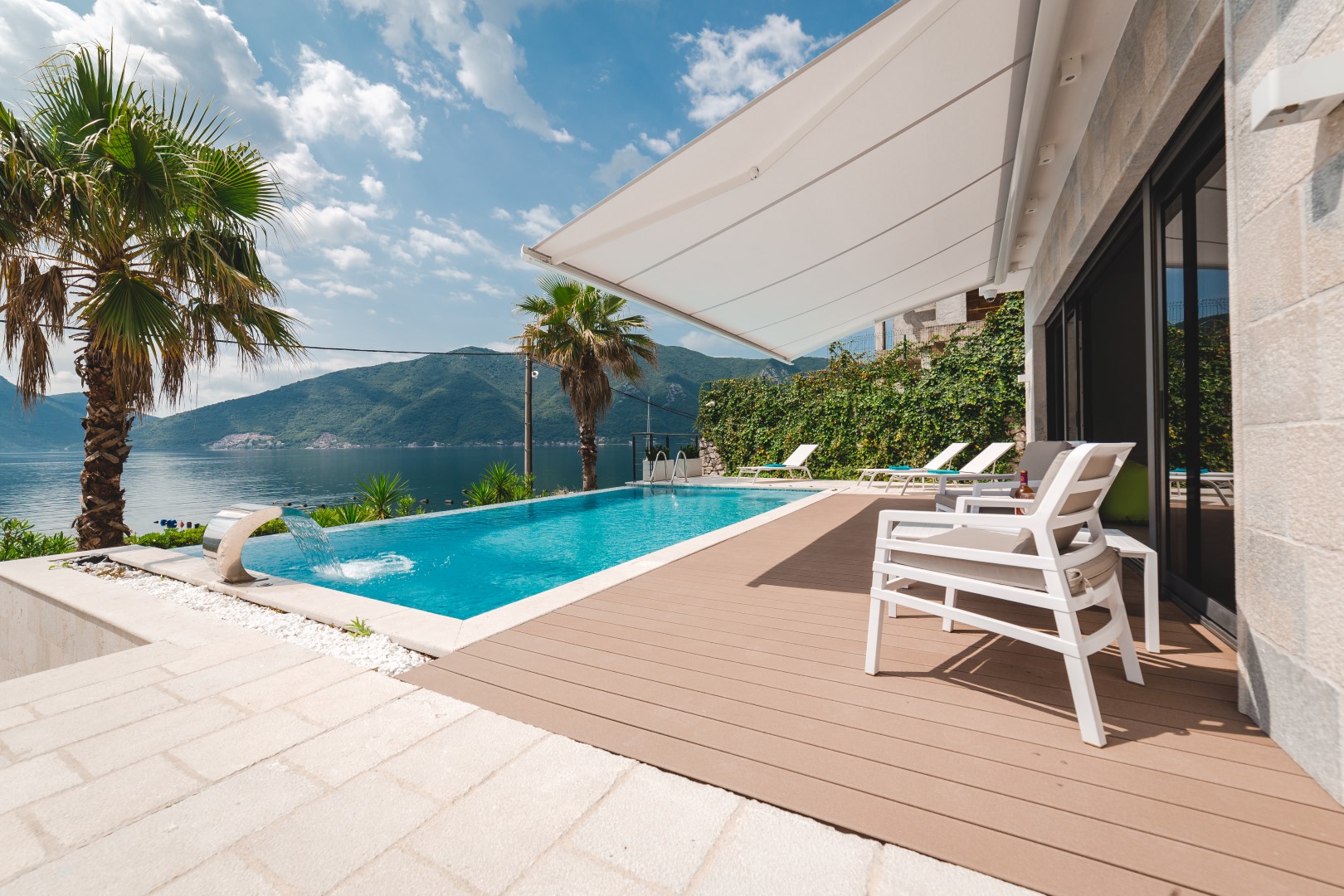 Villa in Strp, Montenegro: a pool with a waterfall, a terrace with sun loungers, and panoramic views of the sea and mountains.