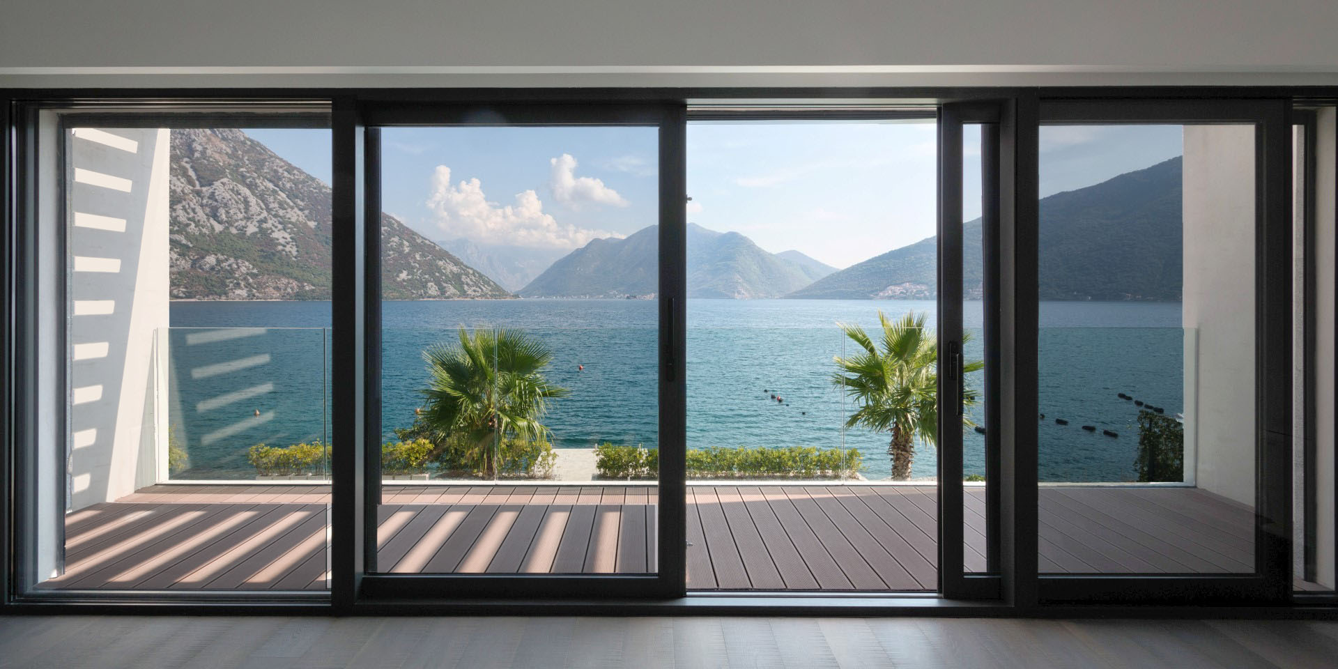 Panoramic sea and mountain view from the villa living room in Strp, Montenegro, with access to a terrace with wooden decking.