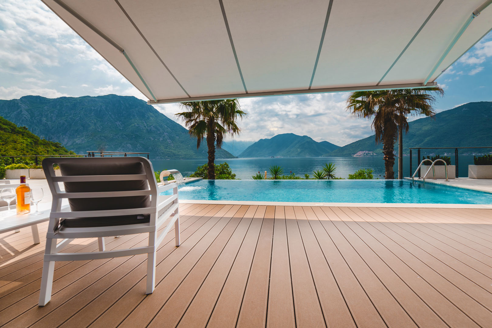 Terrace with a pool and a view of the Bay of Kotor, villa in Strp, Montenegro: wooden deck and sun lounger.