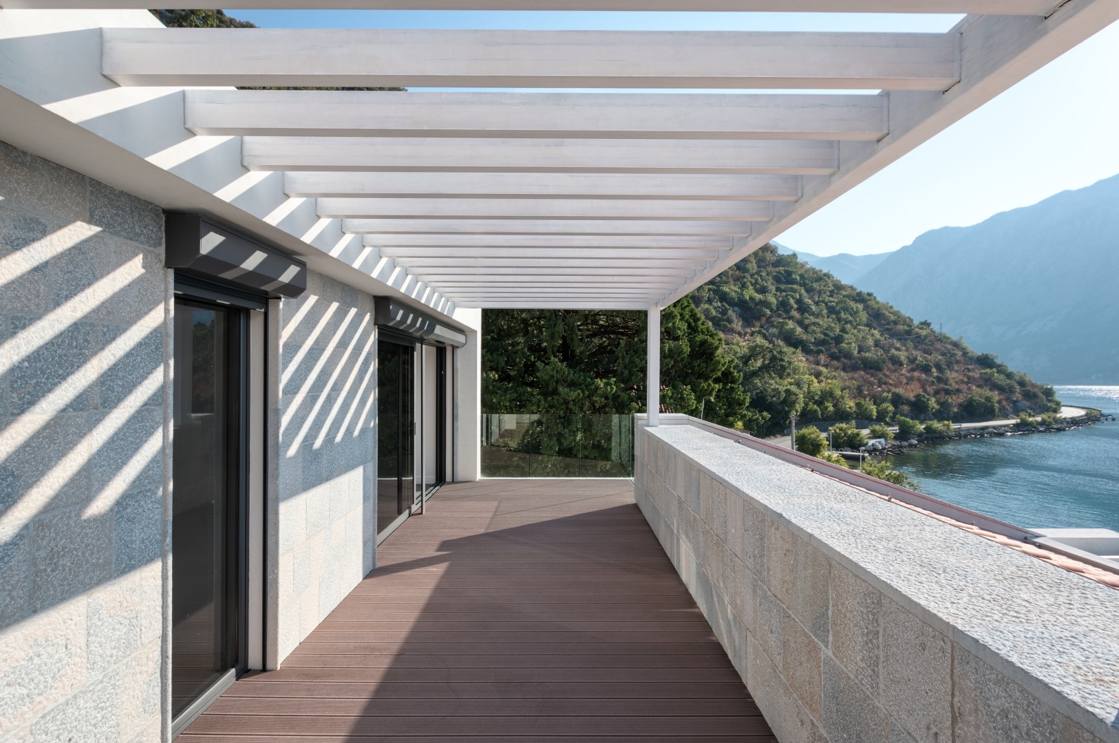 Villa terrace in Strp, Montenegro: wooden decking, stone finishes, pergola, and panoramic views of the Bay of Kotor.