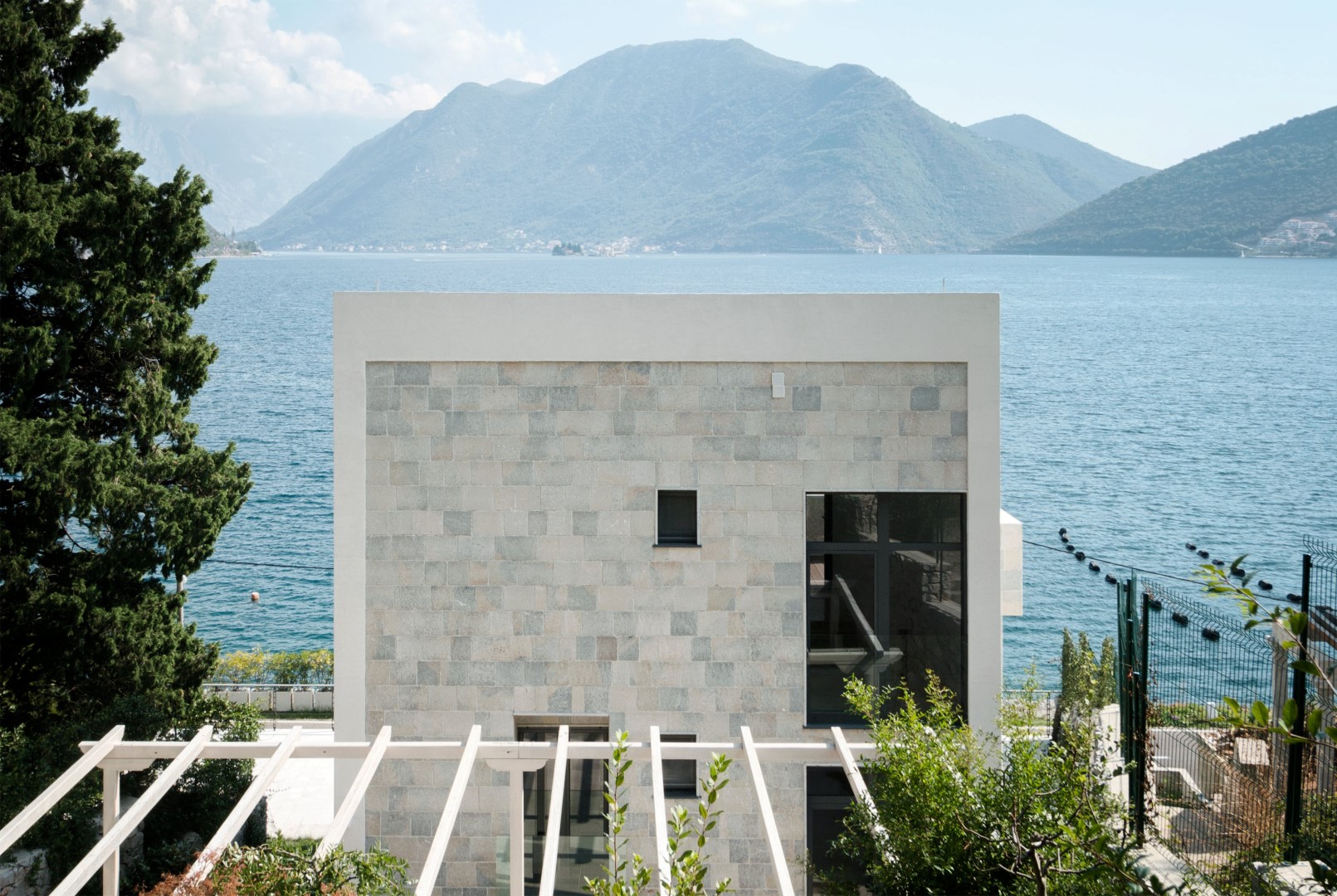 Modern stone villa on the shore of Kotor Bay in Strp, Montenegro, with panoramic sea and mountain views.