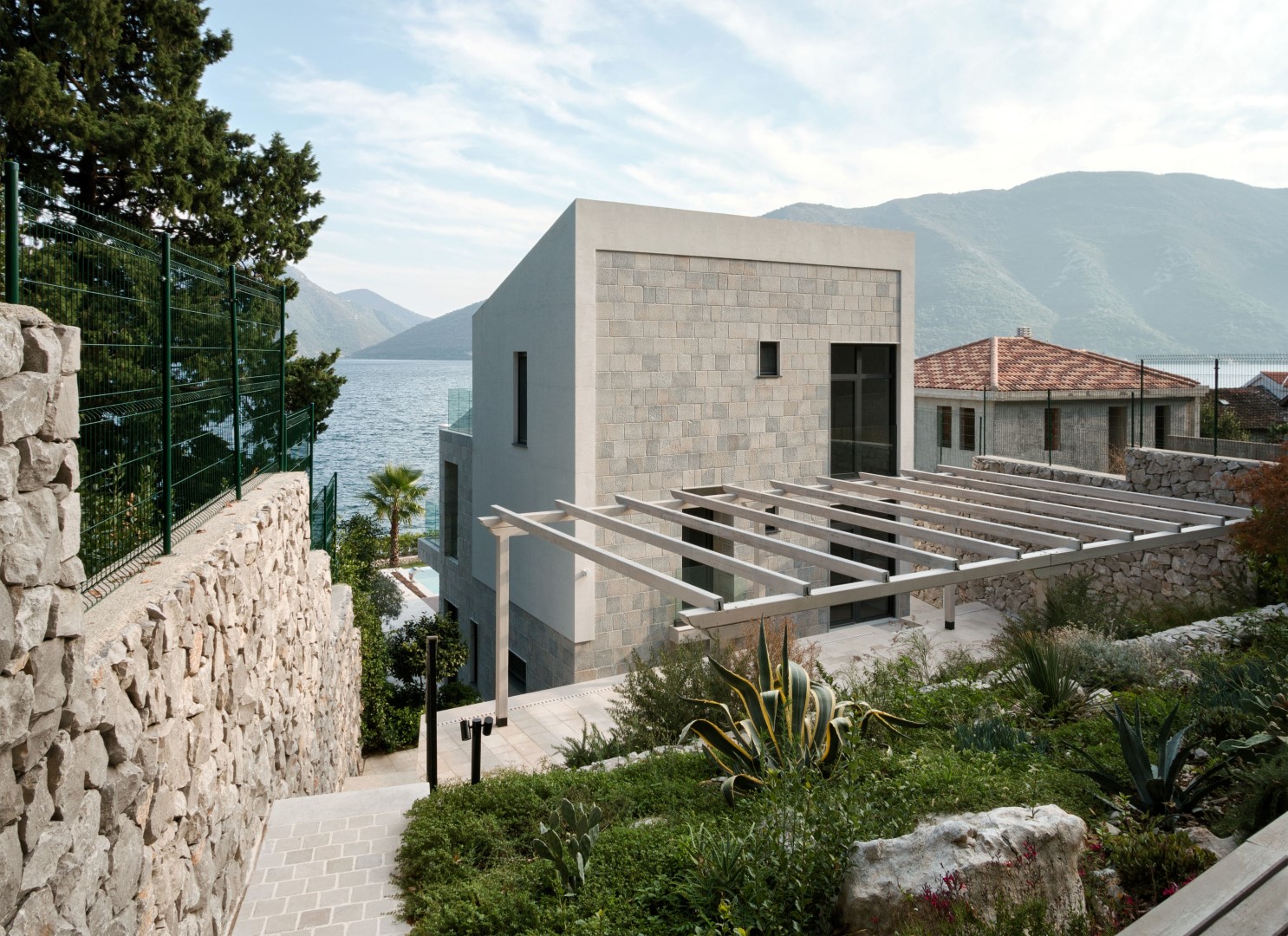 Modern stone villa with a terrace and sea view in the village of Strp, Montenegro, surrounded by a landscaped garden.