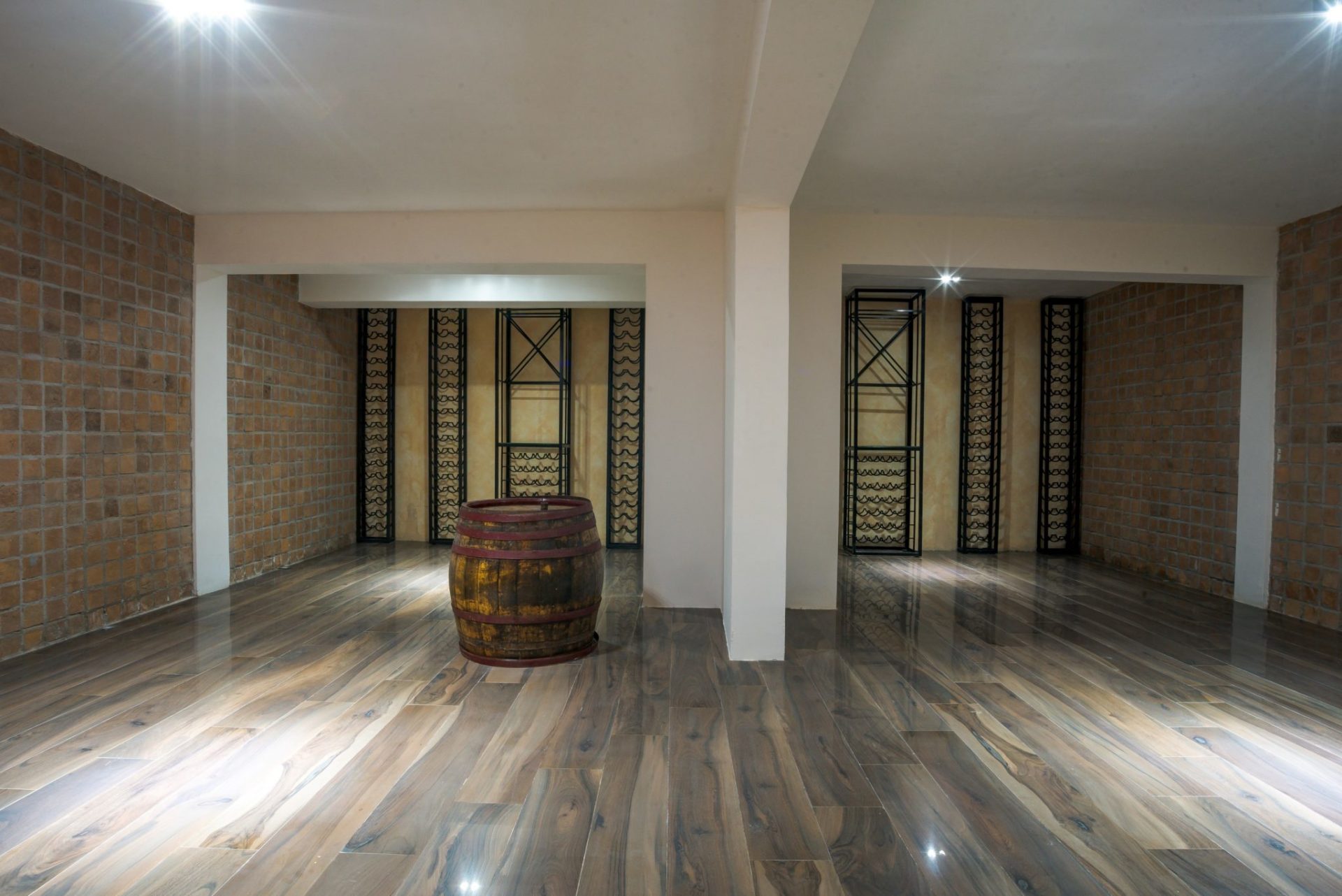 Wine cellar with a wooden barrel and shelving in a luxury villa in Budva, Montenegro, with brick and wood finishes.