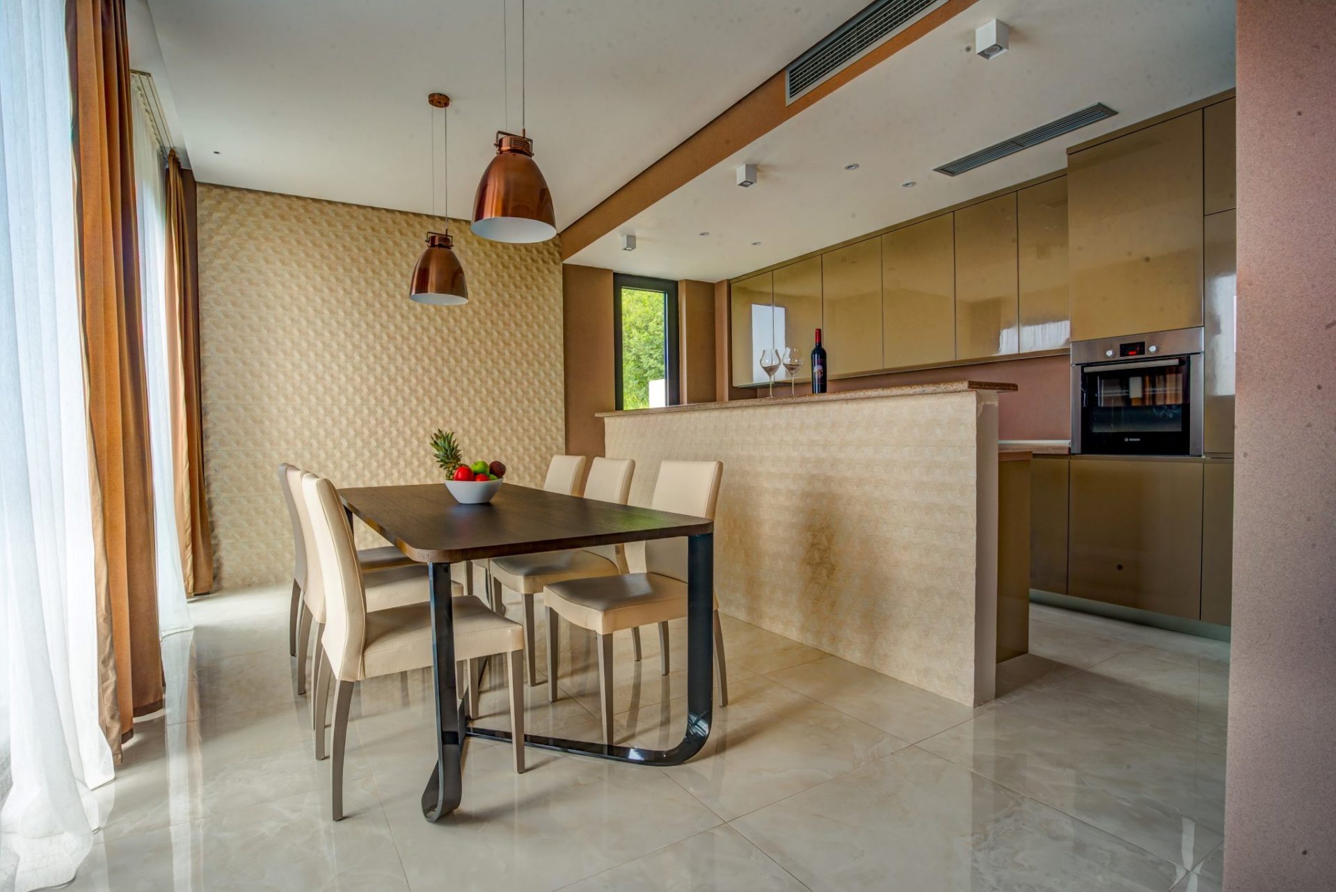 Modern kitchen-dining room with a dining table and glossy cabinetry in a villa in Budva, Montenegro.