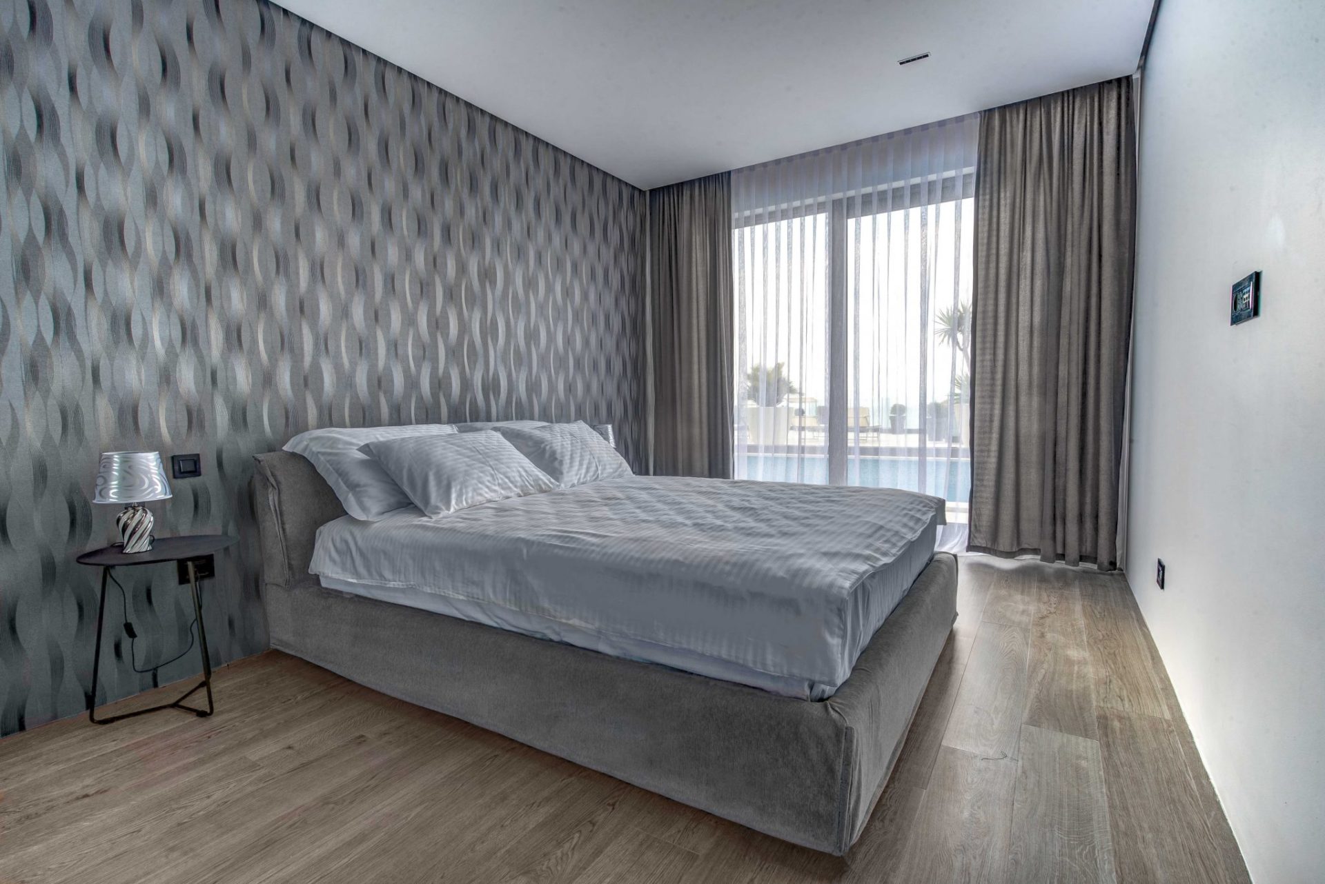 Modern bedroom with a double bed and a panoramic window in a villa in Budva, Montenegro.