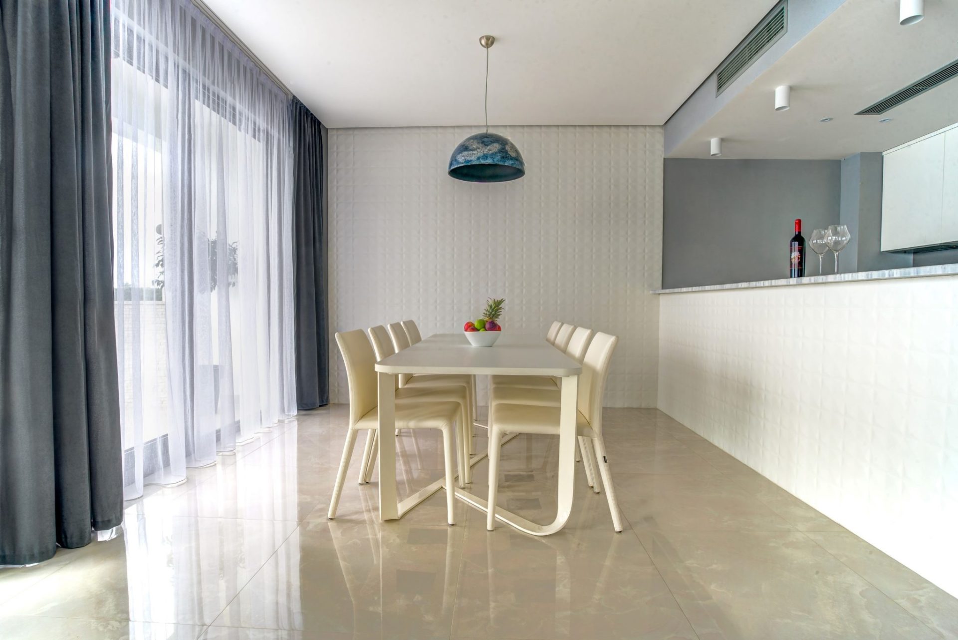 Modern dining area with a white table and chairs in a villa interior in Budva, Montenegro. Panoramic windows and decor.