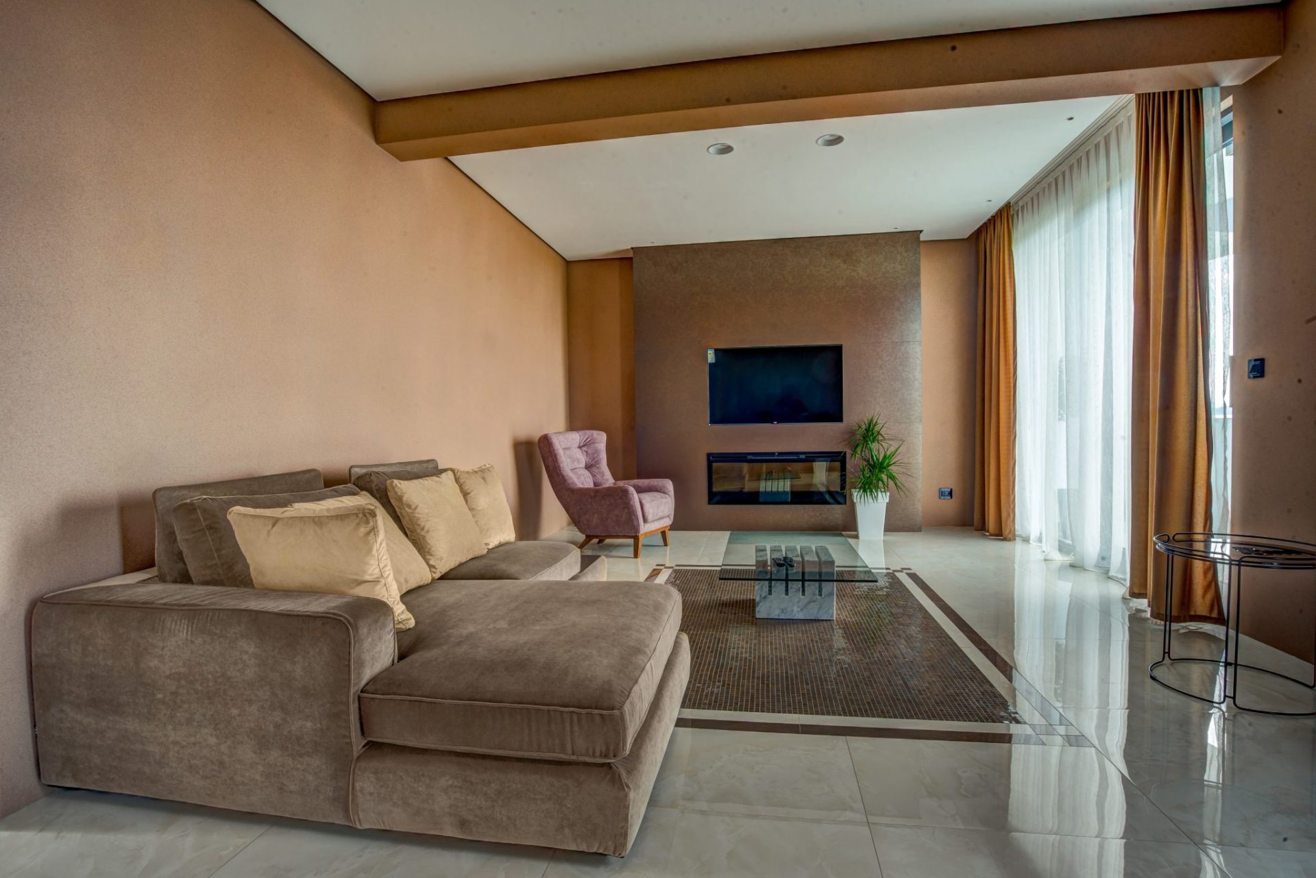 Modern living room with a fireplace and soft seating in an exclusive villa in Budva, Montenegro. Interior with panoramic windows.