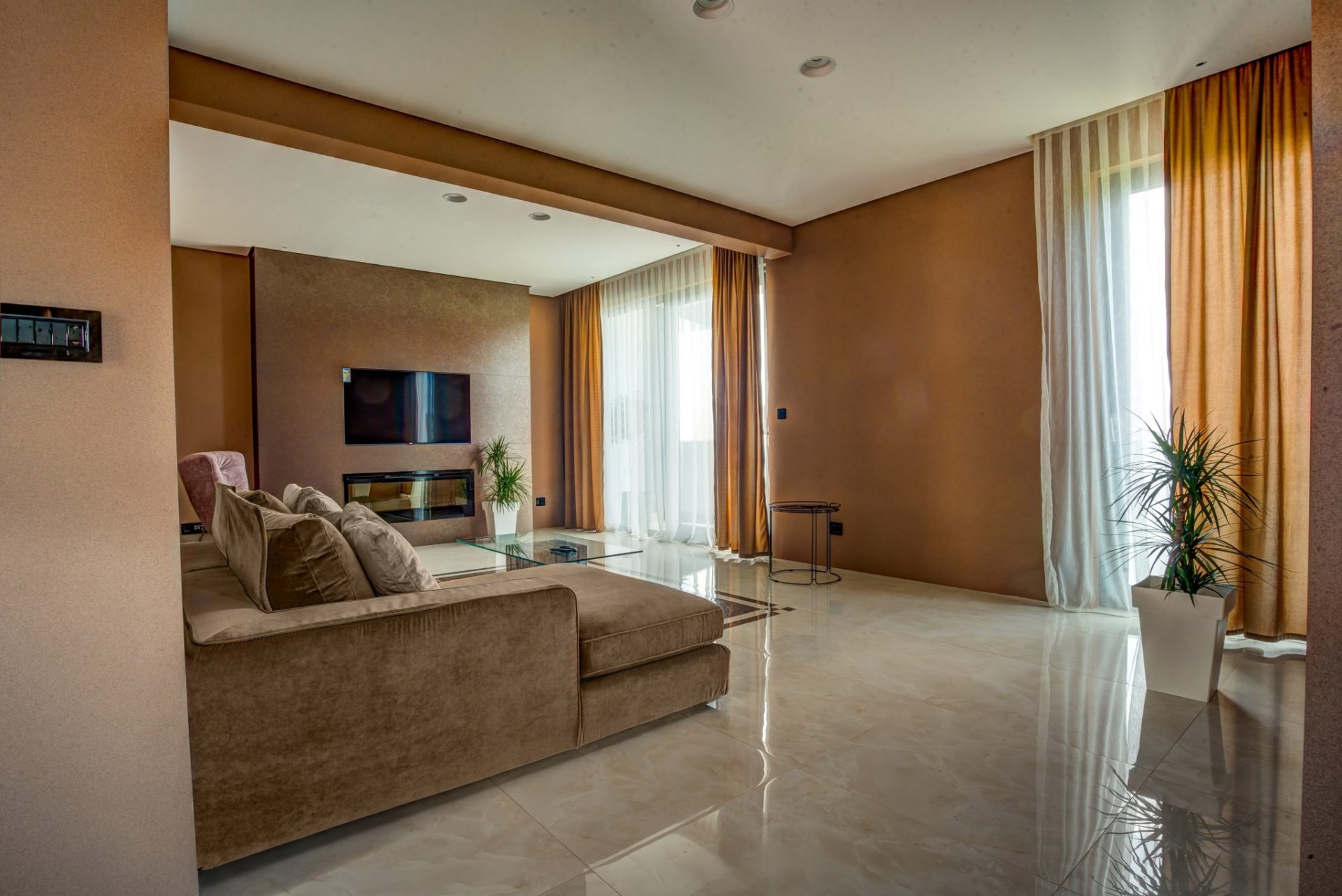 Modern living room with a fireplace and a soft sofa in a villa in Budva, Montenegro: stylish interior, panoramic windows.