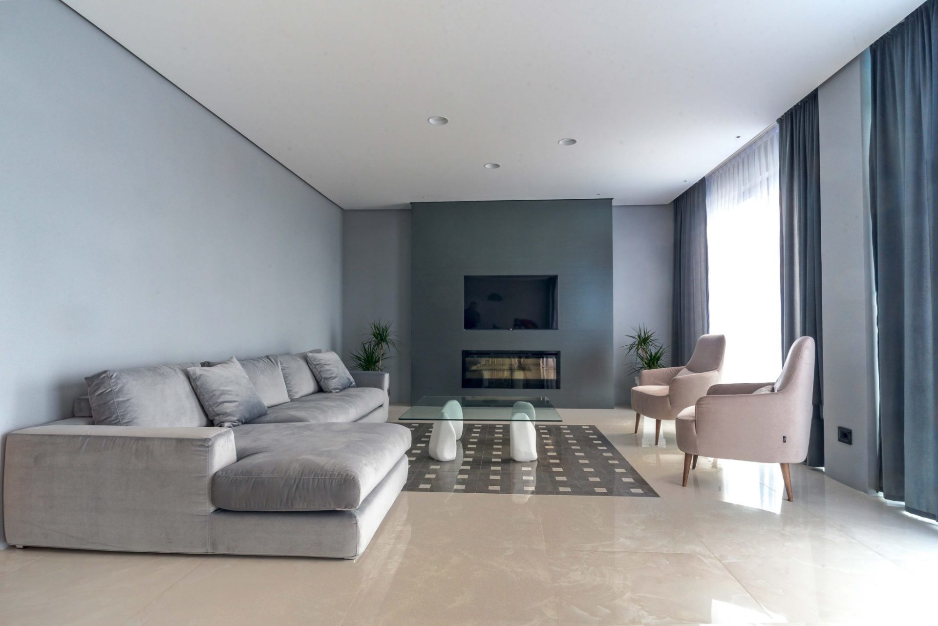 Modern living room with a gray sofa, fireplace, and TV in a luxury villa in Budva, Montenegro. Stylish interior with panoramic windows...