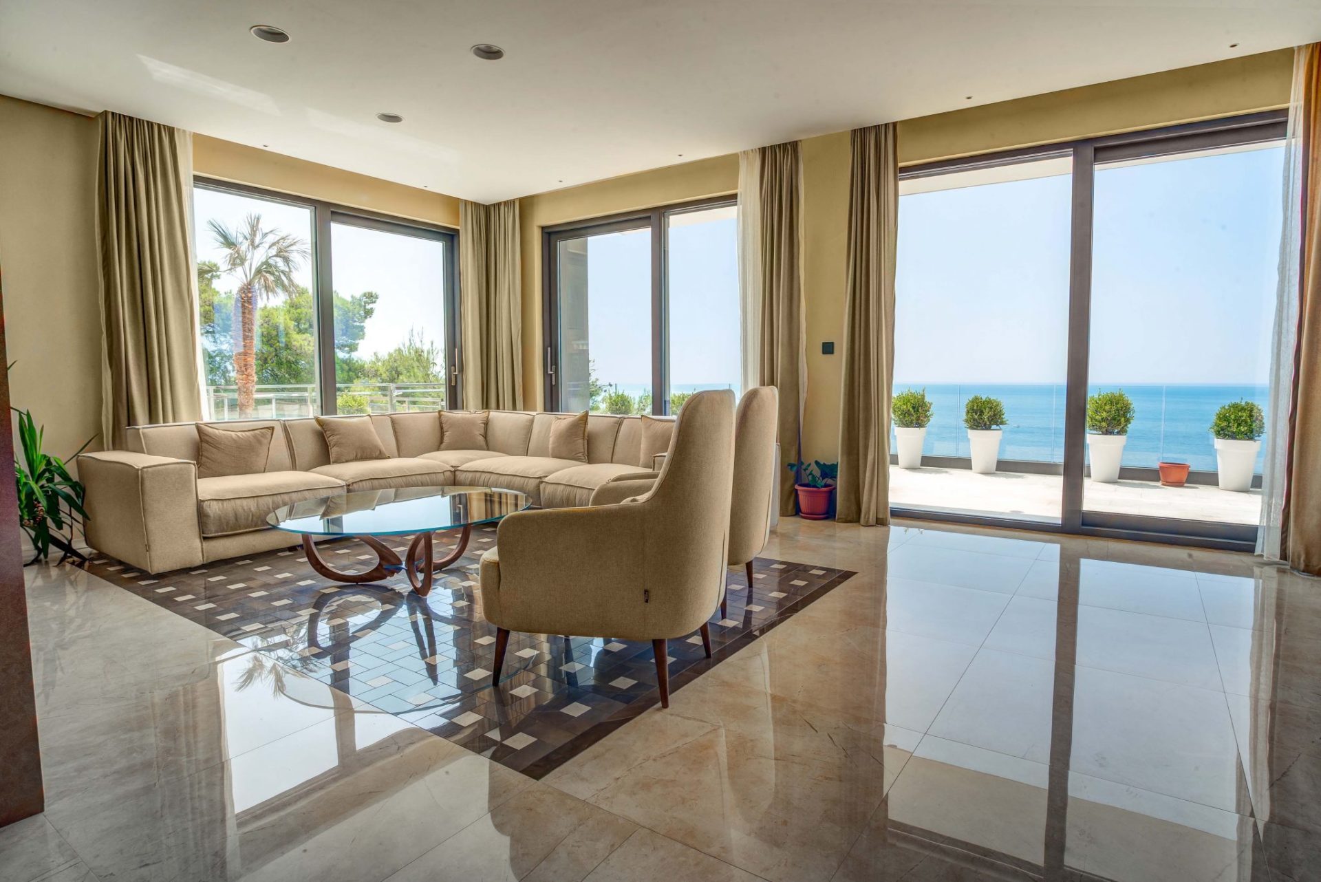Living room with panoramic sea view and terrace in a villa in Budva, Montenegro: light furniture and marble floor.