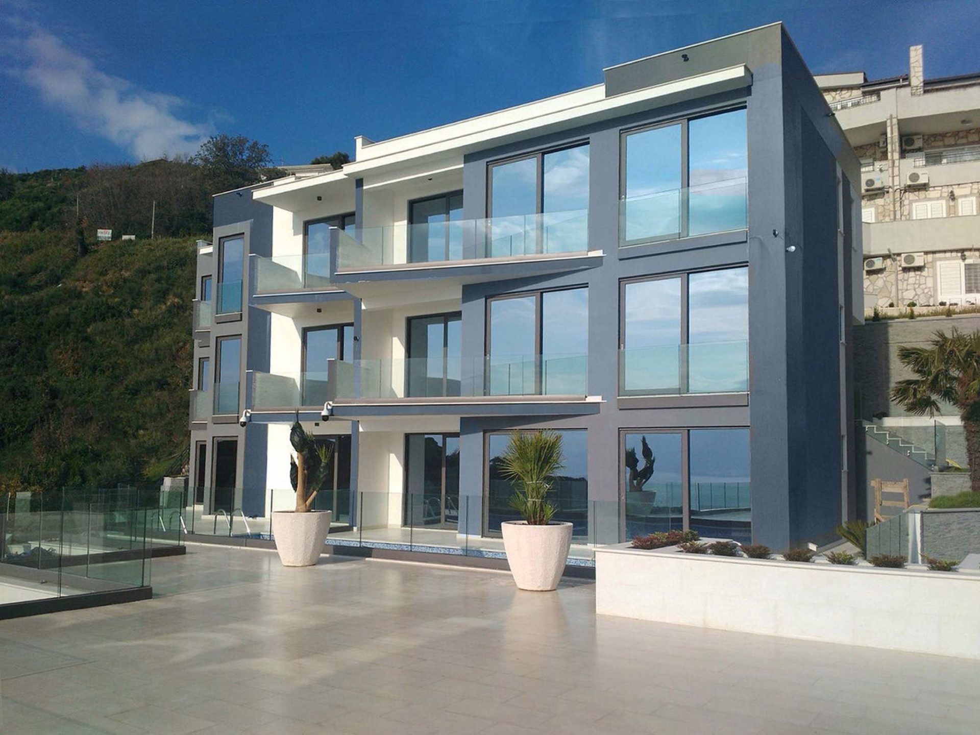 Modern villa in Budva, Montenegro: facade with panoramic windows, glass balconies, and a poolside terrace.