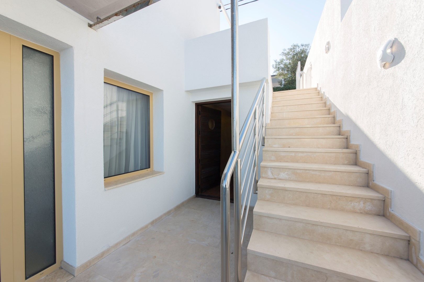 Entrance to a villa in Krašići, Montenegro: white finish, stone staircase with metal railings, and an entrance door.
