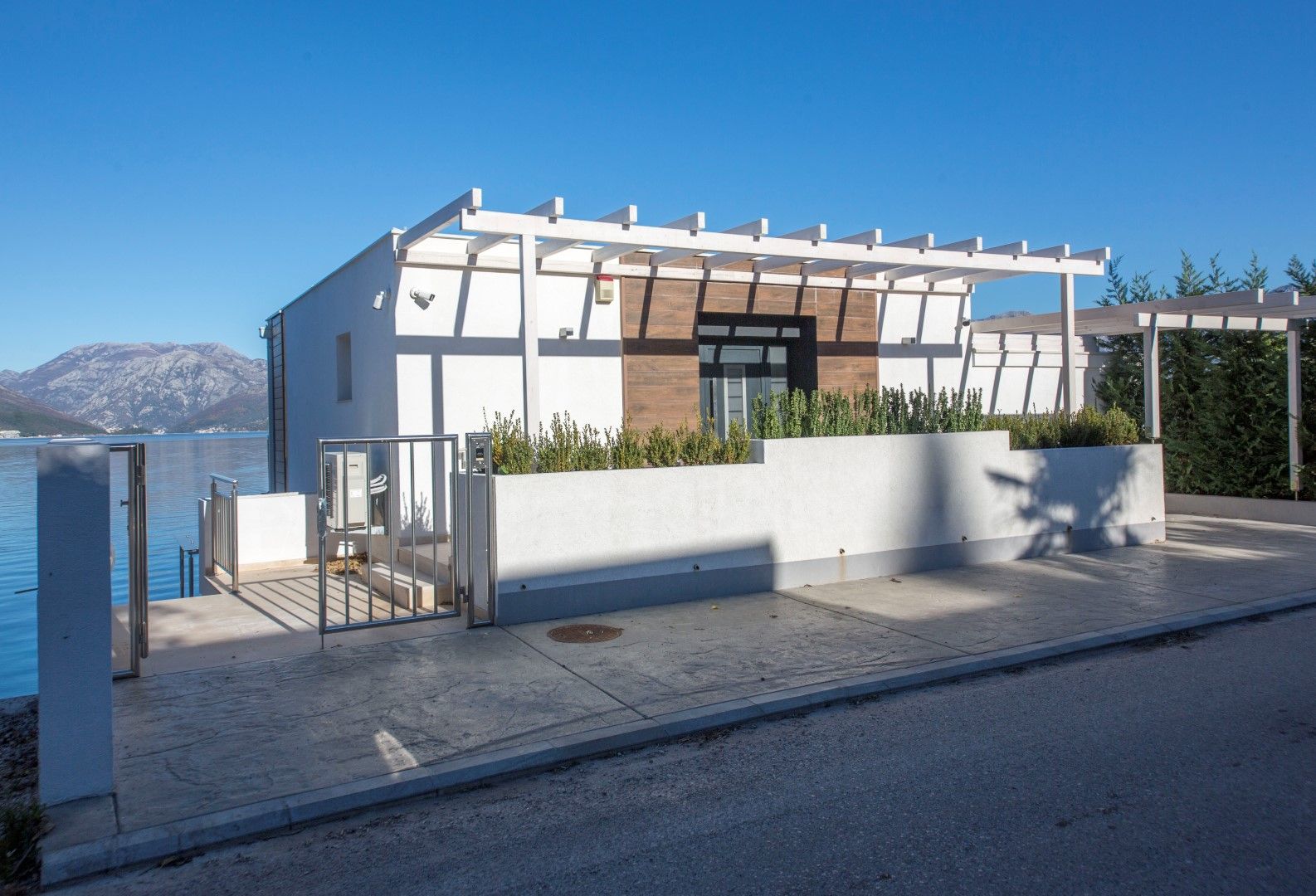Modern villa in Krašići, Montenegro: facade with wooden cladding, pergola, and direct access to the sea.