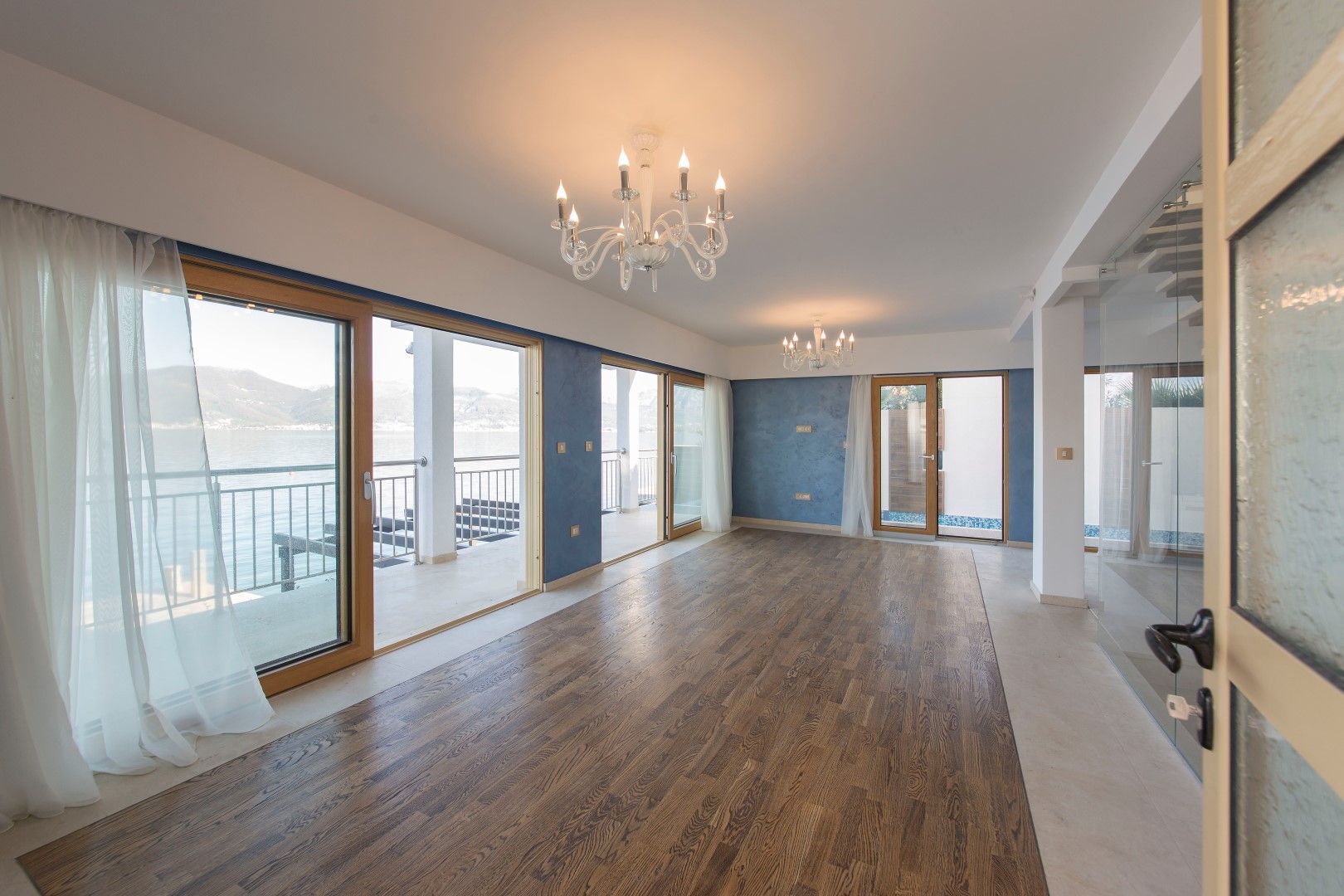 Spacious living room in a villa in Krašići, Montenegro, with panoramic windows, sea views, and access to the terrace.