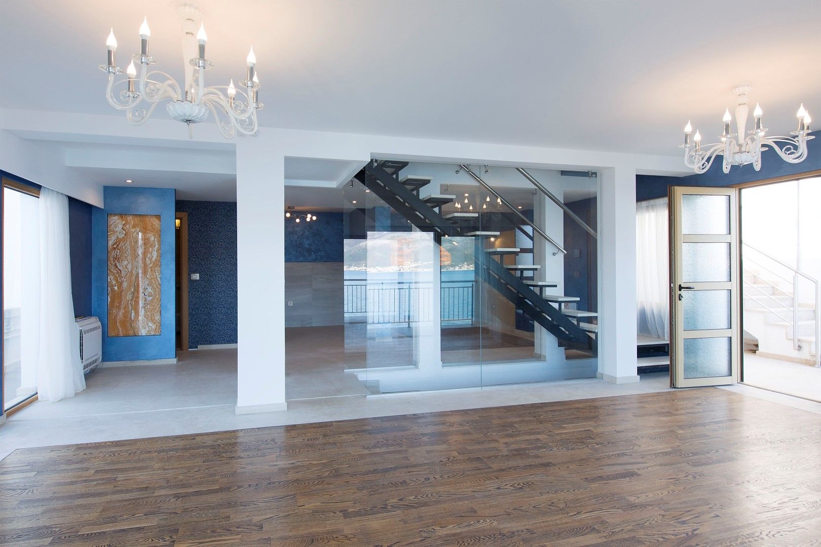 Villa living room in Krašići, Montenegro: modern staircase with glass, parquet flooring, and sea view in the interior.