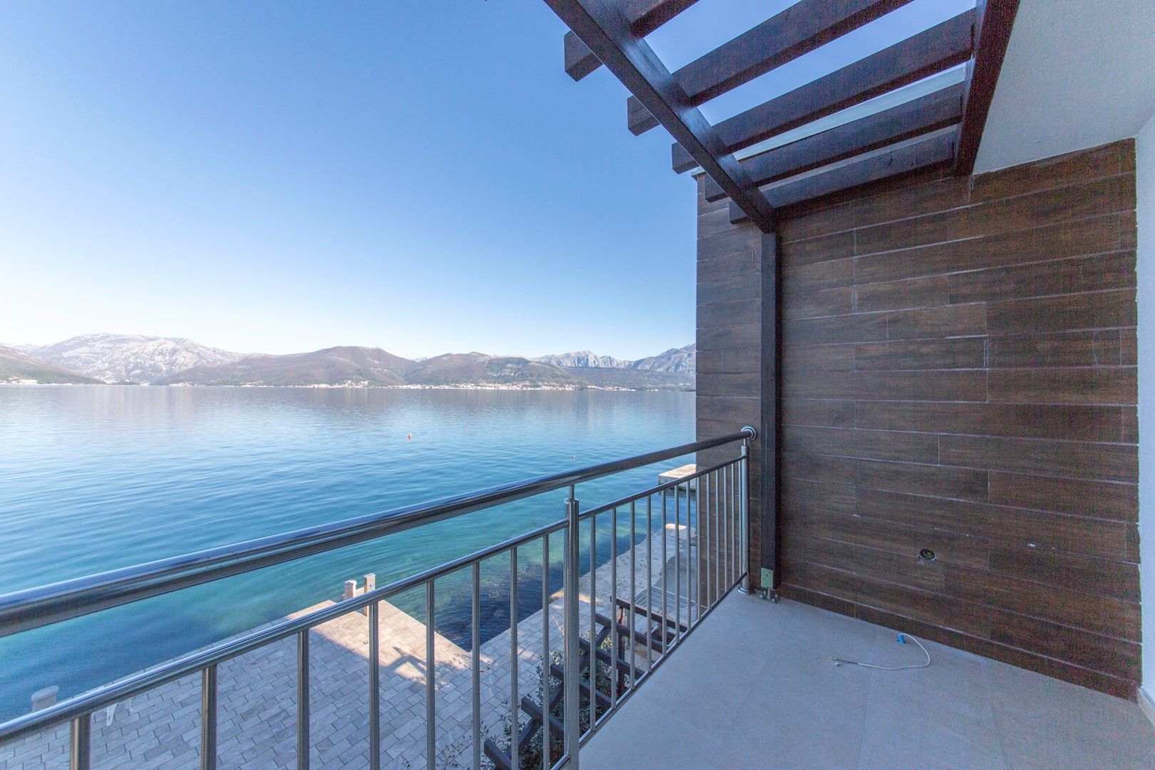 Villa balcony in Krašići, Montenegro: panoramic sea and mountain views, wood finish, modern railing.