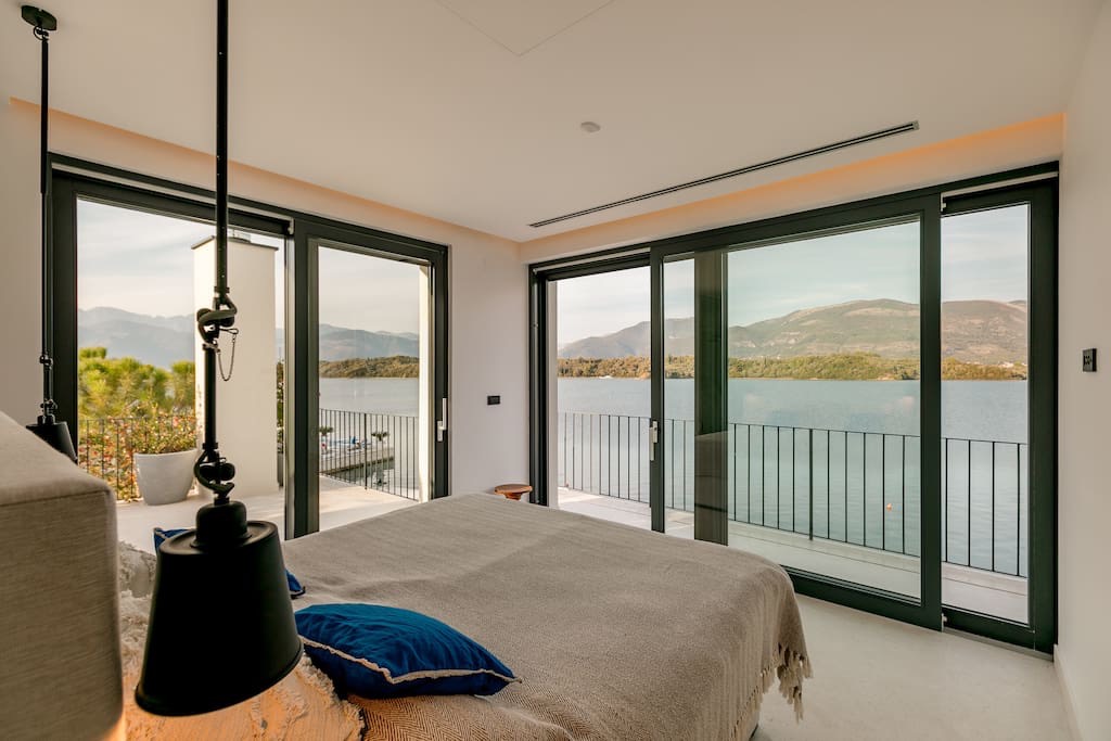 Bedroom in a villa in Lustica, Montenegro: panoramic windows with sea views, modern interior, and access to the terrace.