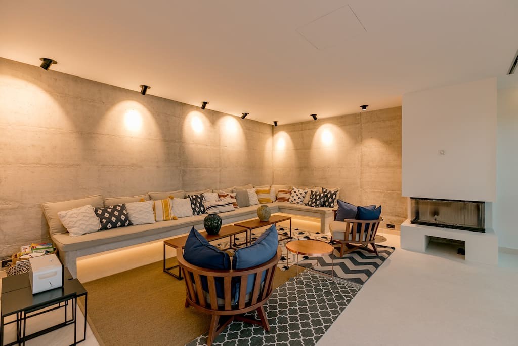 Modern living room with concrete walls, a fireplace, and soft seating in a villa in Luštica, Montenegro.