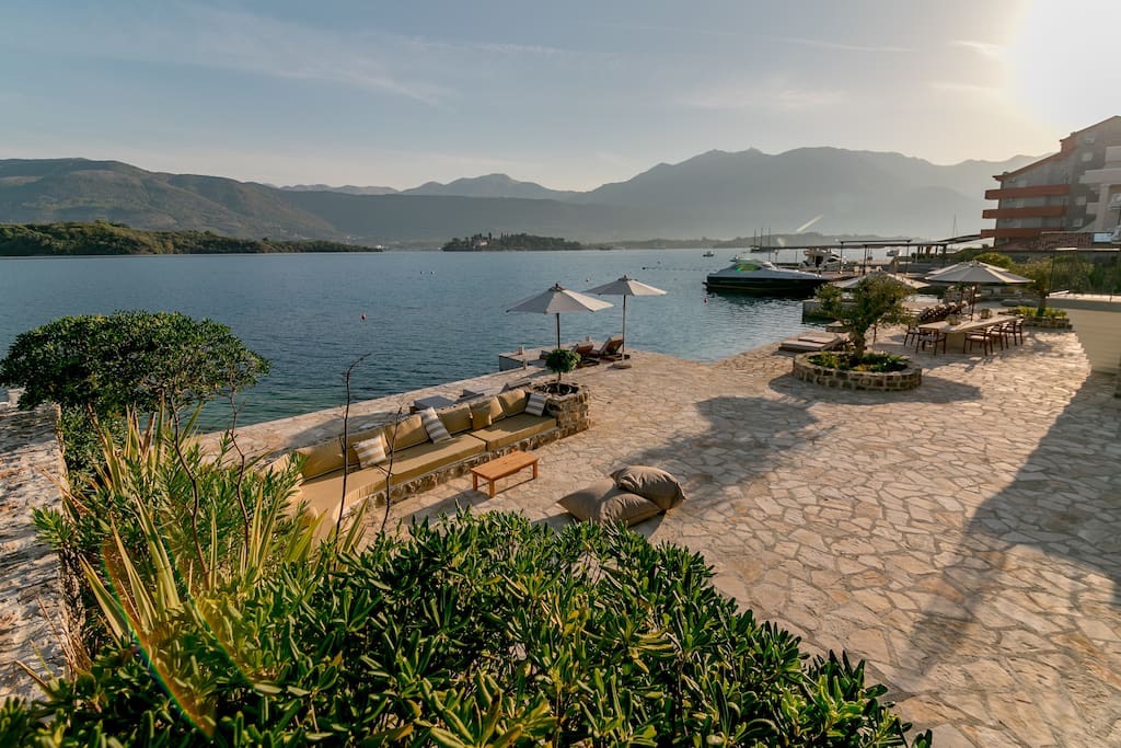 Villa terrace on the first line in Luštica, Montenegro: stone finishes, lounge area with sofas, and views of the sea and mountains.