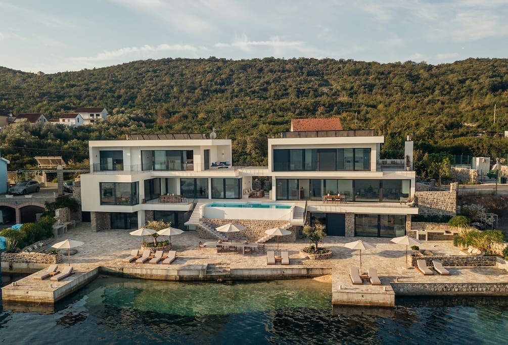 Modern villa on the waterfront in Luštica, Montenegro: pool, terrace with sun loungers, and private sea access.