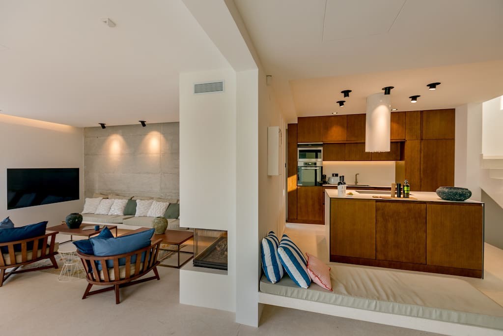 Modern living room with kitchen and fireplace in a villa in Luštica, Montenegro: stylish interior, wooden furniture.