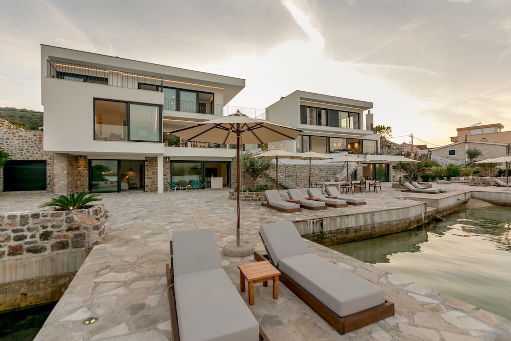Modern villa on the seafront in Luštica, Montenegro: terrace with loungers, stone finishes, and direct access to the sea.