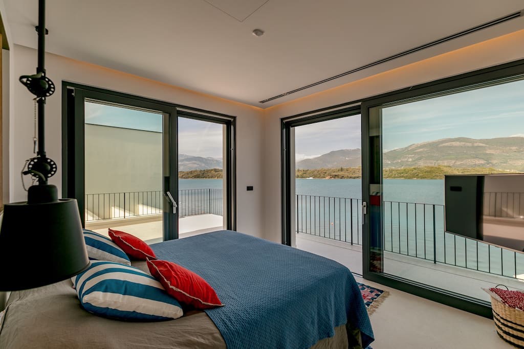 Bedroom with panoramic sea and mountain views in a villa in Lustica, Montenegro: modern interior, access to the terrace.