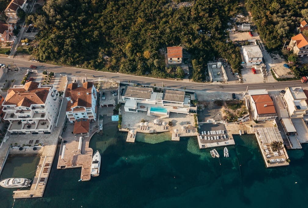 Aerial view of a beachfront villa in Luštica, Montenegro: private beach, pool, pier, and yachts by the sea.