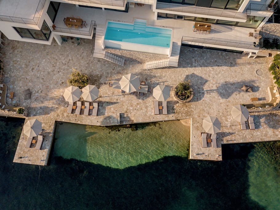 Top view of a luxury villa in Luštica, Montenegro: a pool, a terrace with sun loungers, and private sea access.