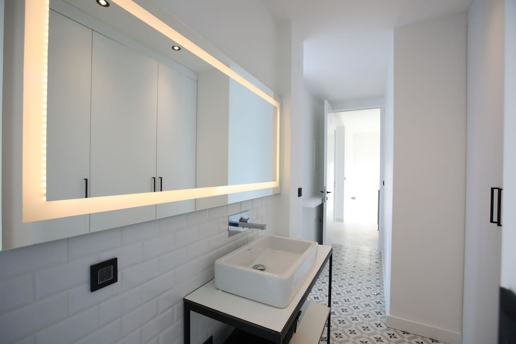 Modern bathroom in a villa in Luštica, Montenegro: vessel sink, backlit mirror, and patchwork-style tile.