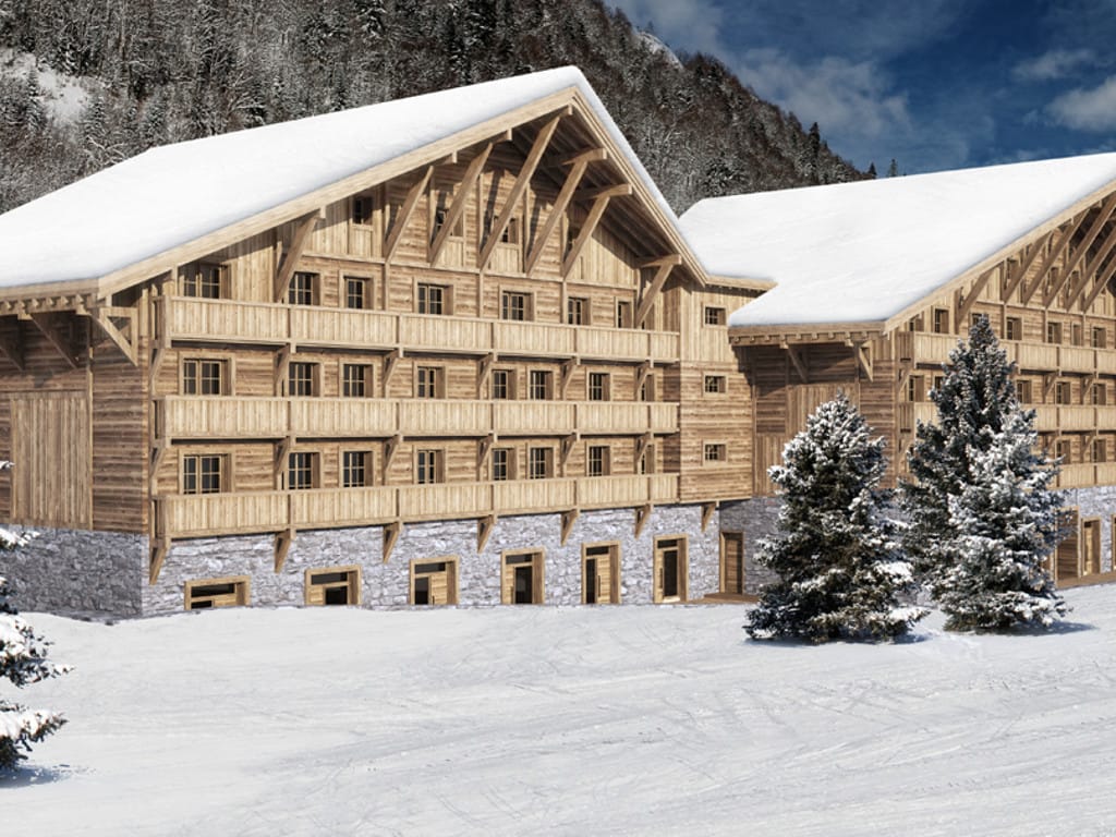 Facade of a wooden chalet-style hotel at the Kolasin ski resort, Montenegro, with snow-covered mountains in the background.