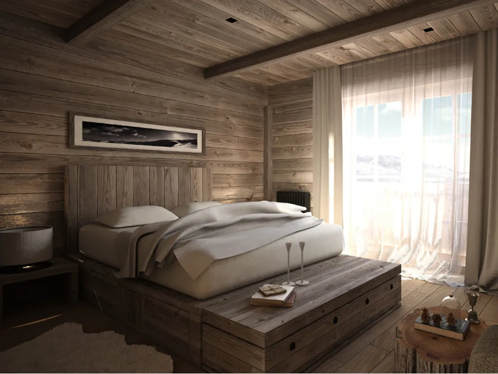 Rustic bedroom with wooden walls and ceiling, featuring a large bed on a platform, nightstand, framed art, and a window with sheer curtains.