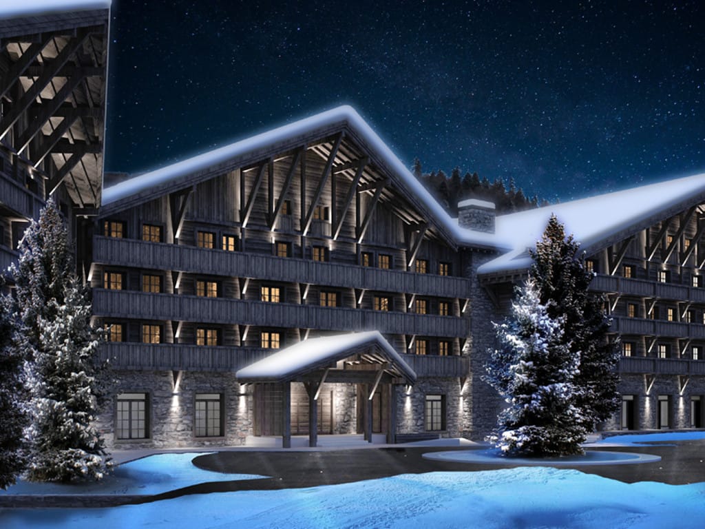 Hotel facade in chalet style in Kolašin, Montenegro: wooden cladding, stone base, and night lighting in the snow.