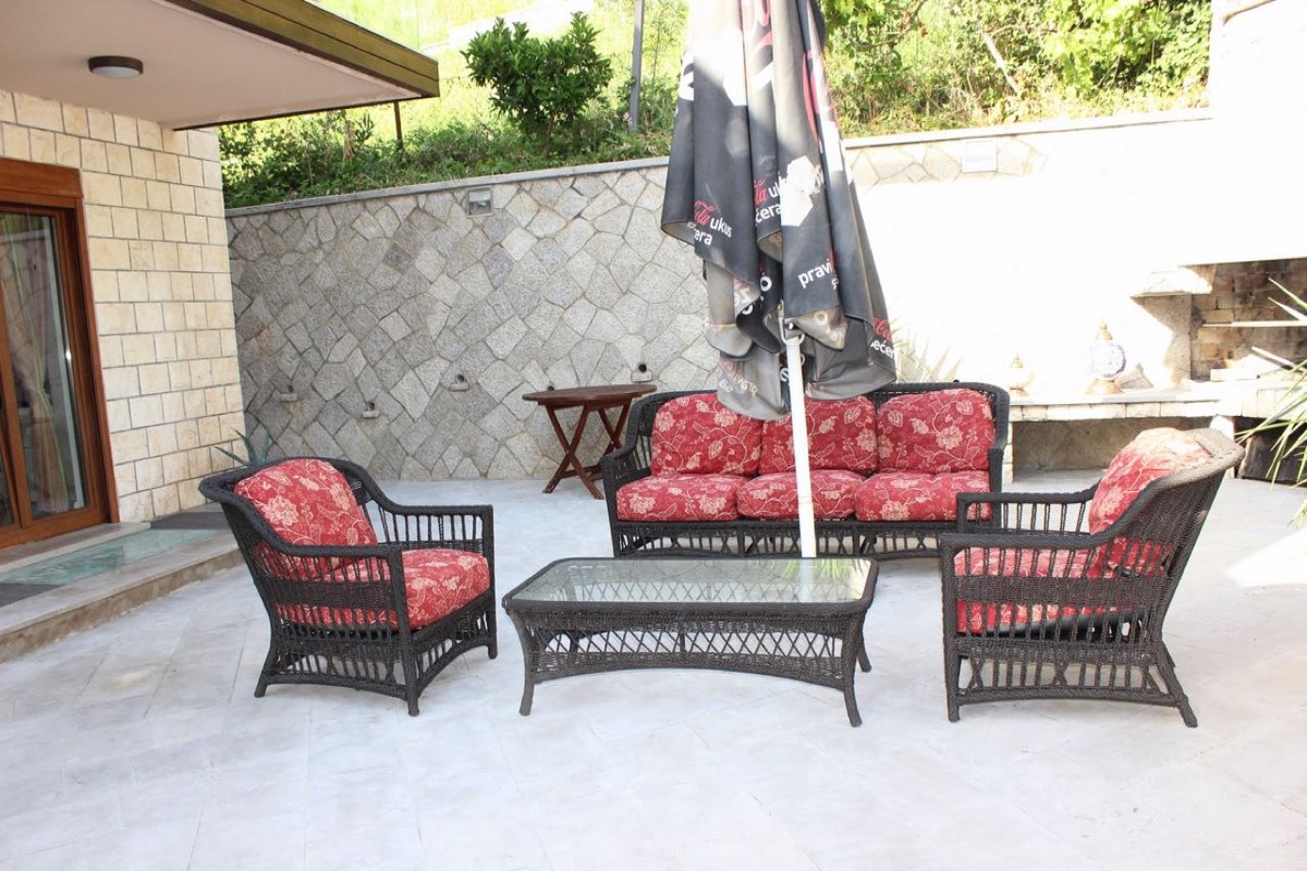 Cozy terrace with wicker furniture and stone finishes at a villa in Budva, Montenegro.