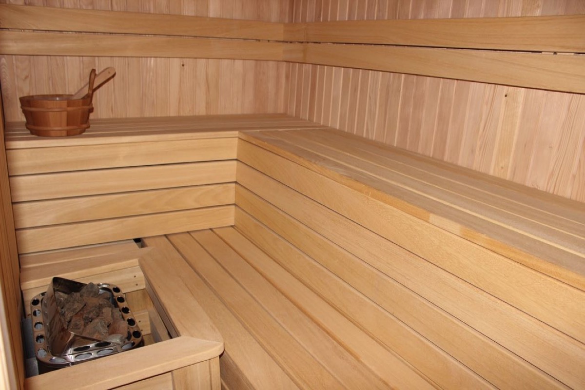 Interior of a modern sauna with wood paneling and a stove in a villa in Budva, Montenegro.