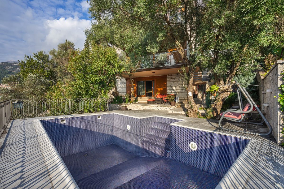 Private pool with mosaic finish and a terrace with swings by a villa in Budva, Montenegro, surrounded by olive trees.